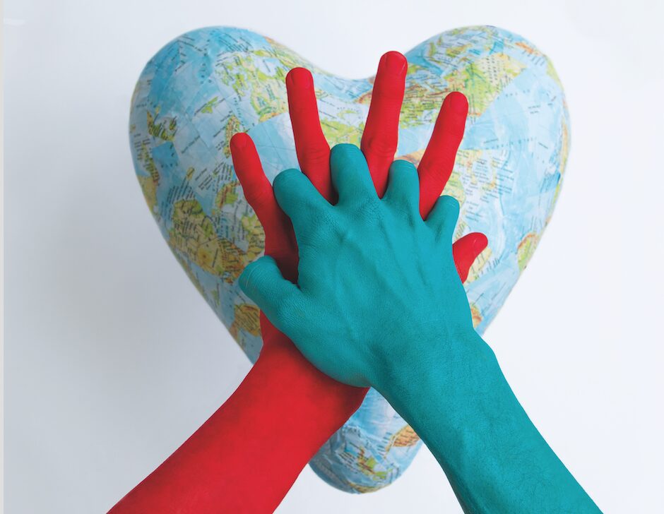 Twee handen ineengevouwen met achtergrond een hart van de wereld