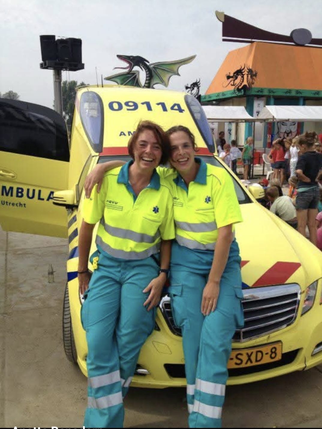 Ambulanceverpleegkundige Anette staat voor een ambulance met haar collega in een oud ambulance uniform.