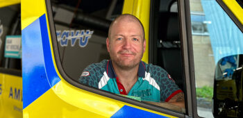 Ambulanceverpleegkundige Jorre poseert voor de ambulance
