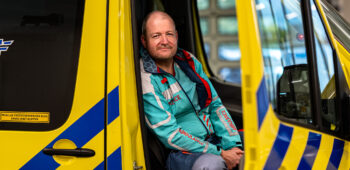 Ambulanceverpleegkundige Jorre zit in de ambulance en kijkt in de camera