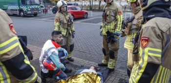 Ambulancepersoneel en brandweer bekommeren zich om een slachtoffer onder een warmtedeken