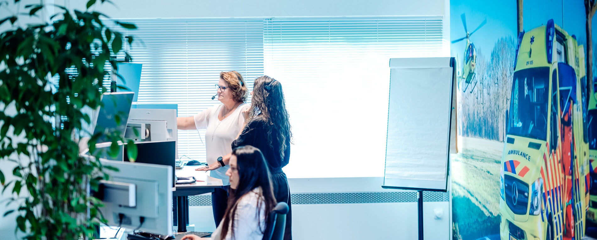 In het 'opleidingen' gedeelte op de meldkamer is te zien hoe een docent instructies geeft aan een verpleegkundig meldkamercentralist in opleiding.