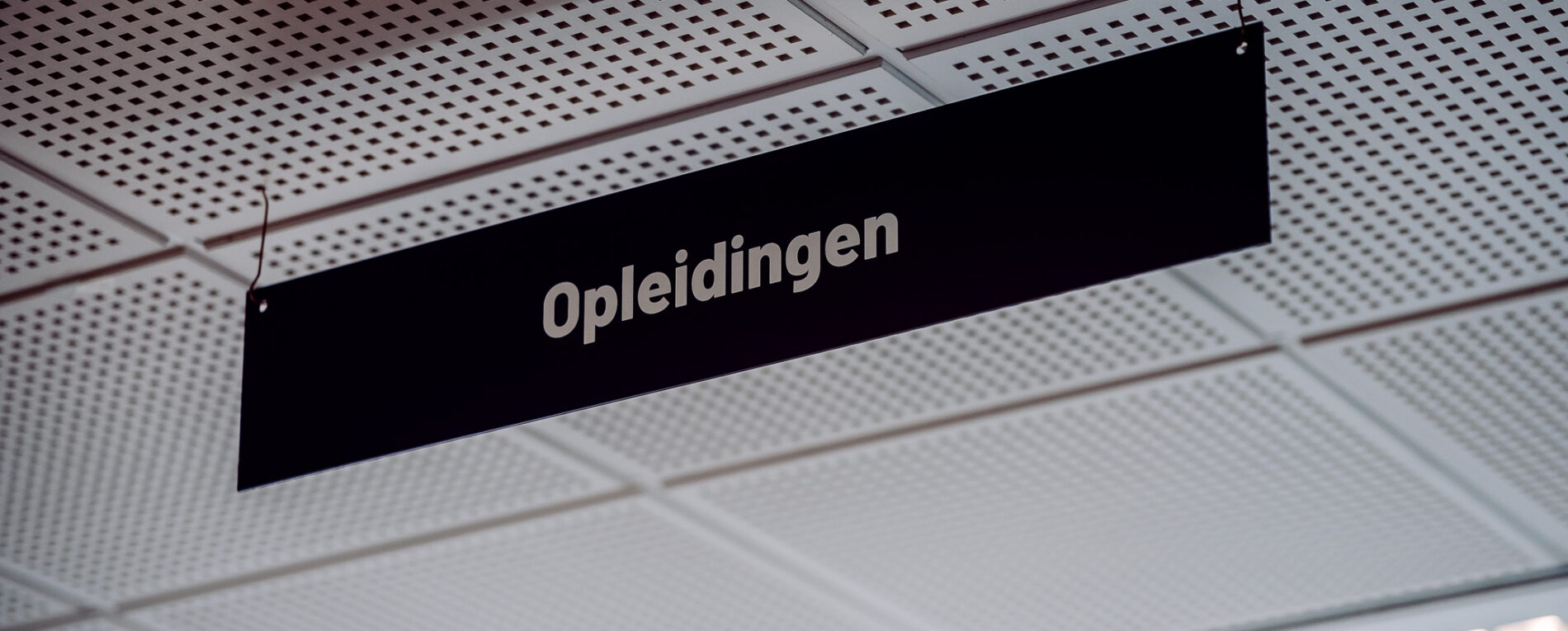 Aan een plafond hangt een bord met daarop 'opleidingen'.