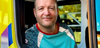 Ambulanceverpleegkundige kijkt door het raam van de ambulance naar buiten.