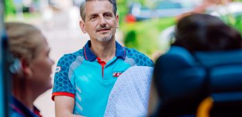 Een ambulancechauffeur en ambulanceverpleegkundige rijden een patiënt op de brancard in de ambulance.